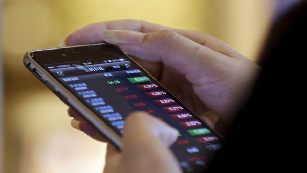 A man checks share prices on his mobile phone while waiting for his coffee at a Starbucks branch in Beijing July 16, 2015. - Sputnik International