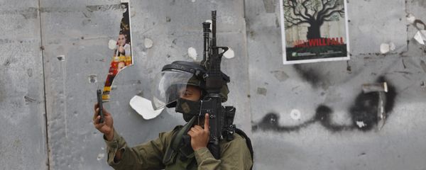 An Israeli soldier takes a photograph with his mobile phone during clashes with Palestinian demonstrators in the West Bank city of Bethlehem on Tuesday, Oct. 13, 2015. A pair of Palestinian men boarded a bus in Jerusalem and began shooting and stabbing passengers, while another assailant rammed a car into a bus station before stabbing bystanders, in near-simultaneous attacks Tuesday that escalated a monthlong wave of violence - Sputnik International