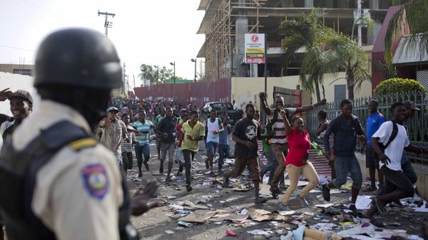 A police officer looks on as a crowd enters the Delimart supermarket complex, which had been burned during two days of protests against a planned hike in fuel prices in Port-au-Prince, Haiti, Sunday, July 8, 2018. - Sputnik International