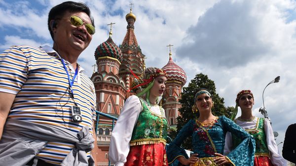 A tourist poses for a picture next to women wearing traditional dresses at Moscow's Red Square on July 10, 2015 - Sputnik International