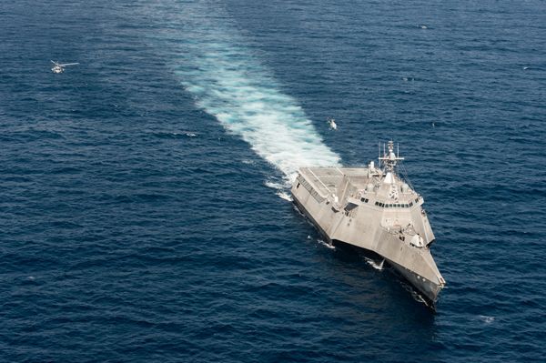 A SeaHawk, to the left, and a Fire Scout, just above the ship, perform simultaneous flight operations. A SeaHawk, to the left, and a Fire Scout, just above the ship, perform simultaneous flight operations. - Sputnik International