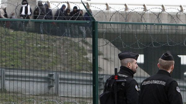 Migrants, background, watch French gendarmes patrolling on the road leading to the port in Calais, northern France, Friday Feb.2, 2018. Police reinforcements are arriving in the French port city of Calais after clashes among migrants left 22 people injured, as the interior minister warned of a worrying spike in violence - Sputnik International