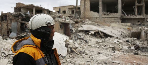 Forty-five-year-old Samir Salim (L) who along with his three brothers are members of the White Helmets rescue forces looks out at destroyed buildings in the town of Medeira in Syria's rebel-held Eastern Ghouta area on February 12 2018. - Sputnik International