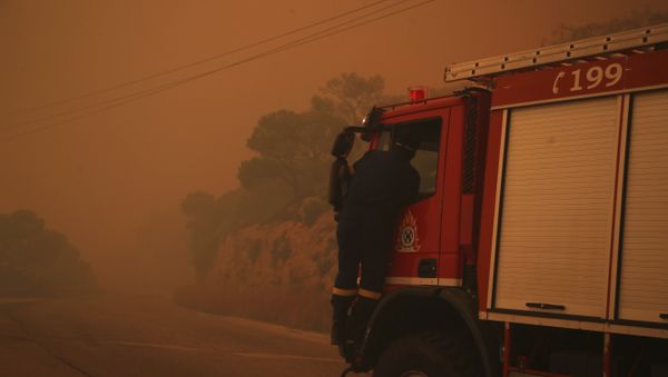 A fire truck is engulfed in a pall of orange smoke on a road near Kineta, west of Athens, Monday, July 23, 2018. - Sputnik International