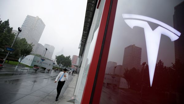 A man walks near a logo of Tesla outside its China headquarters at China Central Mall in Beijing, China July 11, 2018 - Sputnik International