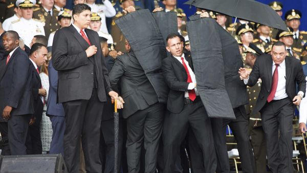 In this photo released by China's Xinhua News Agency, security personnel surround Venezuela's President Nicolas Maduro during an incident as he was giving a speech in Caracas, Venezuela, Saturday, Aug. 4, 2018 - Sputnik International