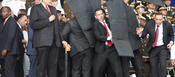 In this photo released by China's Xinhua News Agency, security personnel surround Venezuela's President Nicolas Maduro during an incident as he was giving a speech in Caracas, Venezuela, Saturday, Aug. 4, 2018 - Sputnik International