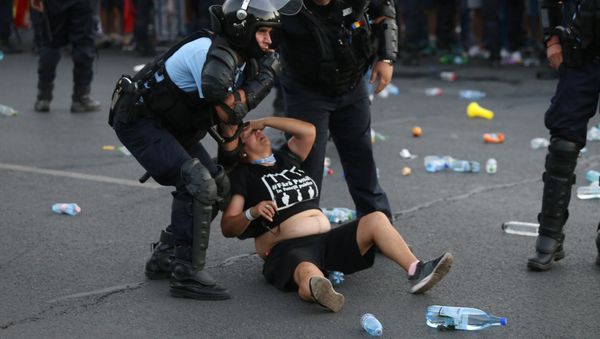 Police stand near protester during a demonstration in Bucharest - Sputnik International