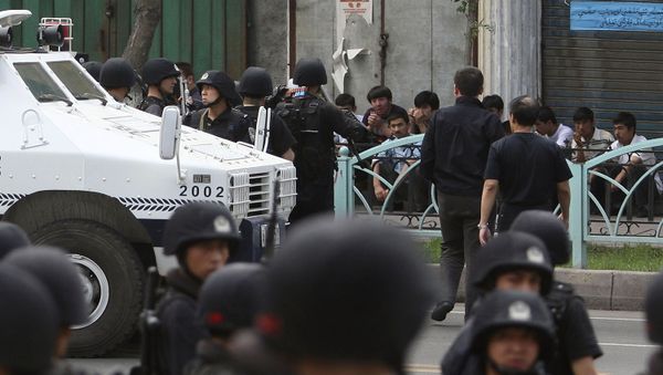 Uyghur protesters, sitting, are detained by security force officers after they marched to protest through the street in Urumqi, western China's Xinjiang province (File) - Sputnik International