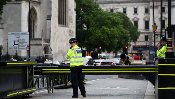 Police officers stand at the vehicle barrier to the Houses of Parliament where a car crashed after knocking down cyclists and pedestrians yesterday in Westminster, London, Britain, August 15, 2018 - Sputnik International