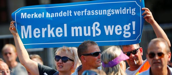 People hold a banner reading: Merkel is acting unconstitutionally, Merkel must leave as they take part in a protest against German Chancellor Angela Merkel as she visits the state parliament in Dresden, Germany August 16, 2018. - Sputnik International