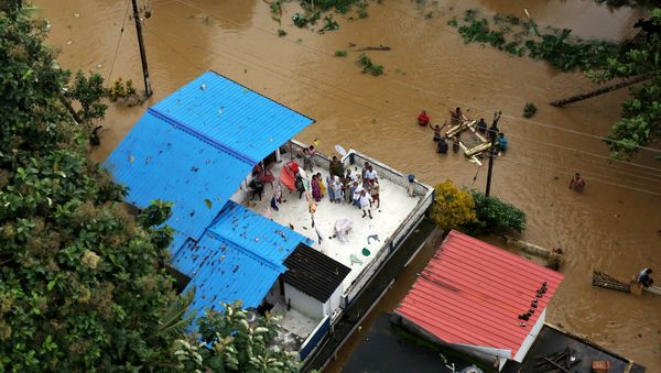 People wait for aid on the roof of their house at a flooded area in the southern state of Kerala, India, August 17, 2018 - Sputnik International