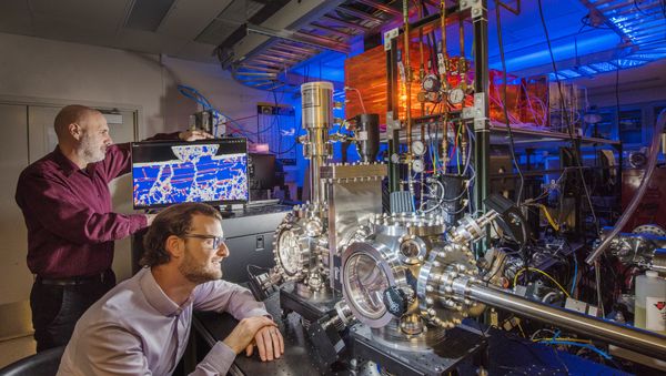 Sandia National Laboratories researchers Michael Chandross, left, and Nicolas Argibay show a computer simulation and an ultrahigh vacuum tribometer used in friction and wear testing - Sputnik International
