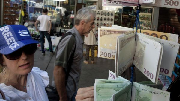 A woman wearing a hat in the colors of Greece's national flag, looks at wallets designed as Euro banknotes on display, outside a kiosk in central Athens - Sputnik International