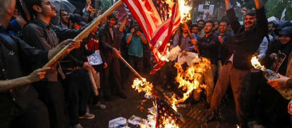Iranians burn US flags during an anti-US demonstration outside the former US embassy headquarters in the capital Tehran on May 9, 2018. - Sputnik International