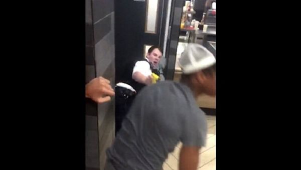After a man in white is pictured kicking one of the police officers, another onlooker (pictured in grey with pink balloon in his mouth) approaches the two PCs - Sputnik International