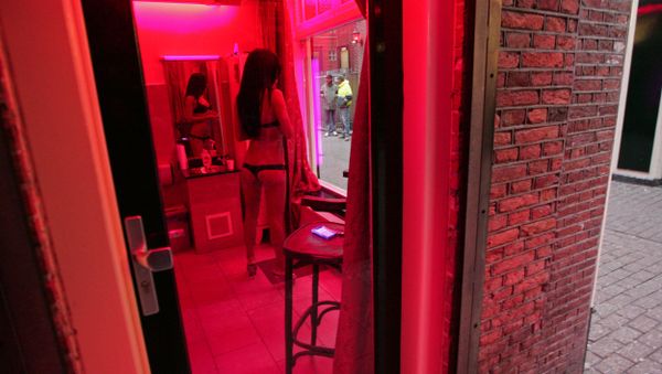 A prostitute waits for clients behind her window in the red light district of Amsterdam on December 8, 2008. A prostitute waits for clients behind her window in the red light district of Amsterdam on December 8, 2008. - Sputnik International