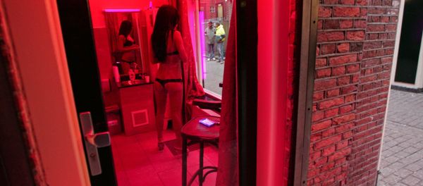 A prostitute waits for clients behind her window in the red light district of Amsterdam on December 8, 2008. - Sputnik International