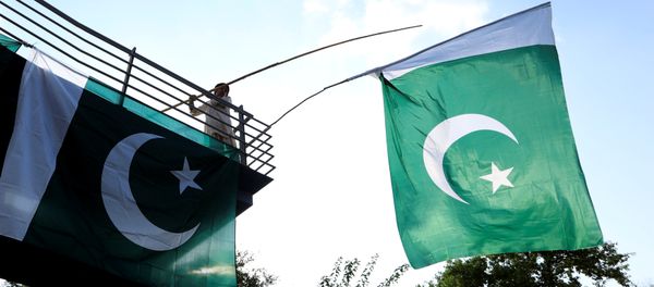 A boy uses a bamboo stick to adjust national flags at an overhead bridge ahead of Pakistan's Independence Day, in Islamabad, Pakistan August 10, 2018 - Sputnik International