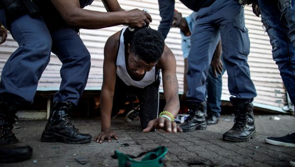 A suspected looter is detained by South African police officers as he emerges from of a looted foreign-owned shop in Soweto, Johannesburg, on August 29, 2018 during unrest that erupted after a foreign shop owner allegedly shot and killed a member of the community during a demonstration - Sputnik International