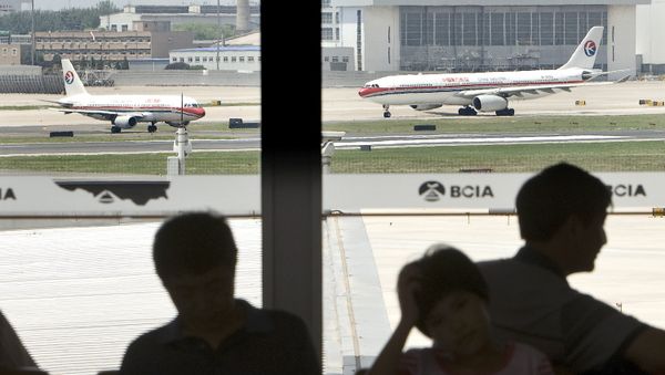 Passengers are seen silhouetted while two China Eastern Airliners prepare to take off at the Beijing Capital International Airport in Beijing, Tuesday, June 9, 2009. China Eastern Airlines is considering merging with smaller rival Shanghai Airlines, reports said Tuesday, as regulators push ahead with plans to revamp the troubled industry. (AP Photo/Andy Wong) - Sputnik International