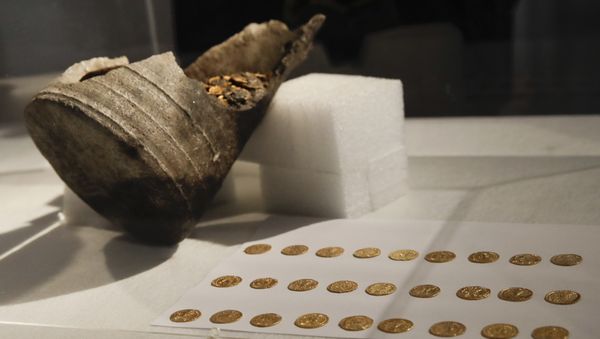 Ancient gold coins are displayed in a plexiglass case during a news conference, in Milan, Italy, Monday, Sept. 10, 2018. Hundreds of gold coins of the late imperial era, kept in a soapstone vessel of uncommon shape were discovered last Wednesday in the center of Como, northern Italy, during restructuring works inside a theater. (AP Photo/Luca Bruno) - Sputnik International
