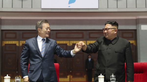 South Korean President Moon Jae-in, left, and North Korean leader Kim Jong Un hold their hands after watching the mass games performance of The Glorious Country at May Day Stadium in Pyongyang, North Korea, Wednesday, Sept. 19, 2018. Unification flag symbol at top centre. - Sputnik International