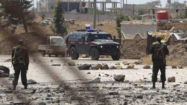 Syrian army soldiers stand guard as Russian military police vehicle passes by near the town of Alhureyeh, Syria, Tuesday, Aug. 14, 2018 - Sputnik International