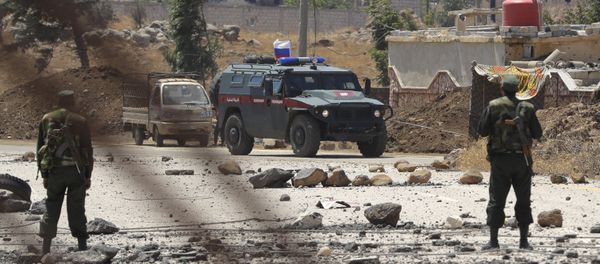 Syrian army soldiers stand guard as Russian military police vehicle passes by near the town of Alhureyeh, Syria, Tuesday, Aug. 14, 2018 - Sputnik International
