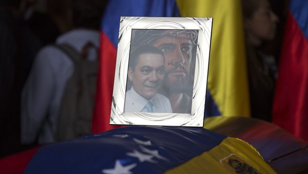A framed portrait of opposition activist Fernando Alban shadowed by an image of Jesus Christ sits on the flag-draped casket containing his remains, during a solemn ceremony at the National Assembly headquarters, in Caracas, Venezuela, Tuesday, Oct. 9, 2018 - Sputnik International