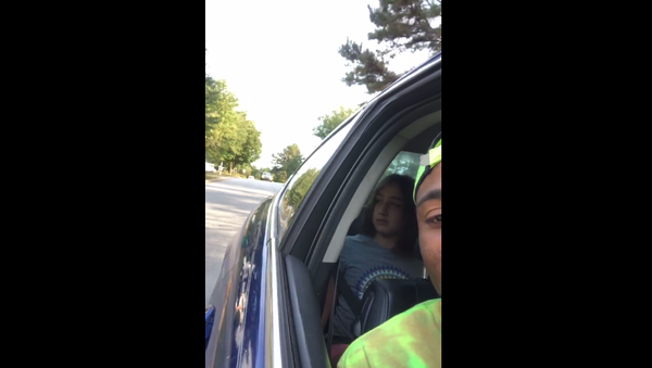 Corey Lewis records a Facebook Live video of an unidentified woman following him for babysitting two white kids. 10-year-old Addison can be seen in the back seat of the car. - Sputnik International
