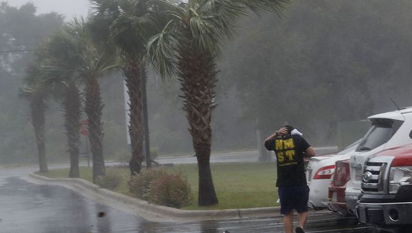 A hubcap blows by as a man runs to his car during Hurricane Michael in Panama City, Fla., Wednesday, Oct. 10, 2018. - Sputnik International