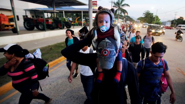 A man carries a child as they move in a caravan toward the United States, in San Pedro Sula, Honduras October 13, 2018 A man carries a child as they move in a caravan toward the United States, in San Pedro Sula, Honduras October 13, 2018 - Sputnik International