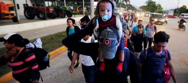 A man carries a child along other Hondurans fleeing poverty and violence, as they move in a caravan toward the United States, in San Pedro Sula, Honduras October 13, 2018 A man carries a child along other Hondurans fleeing poverty and violence, as they move in a caravan toward the United States, in San Pedro Sula, Honduras October 13, 2018 - Sputnik International