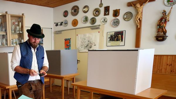 A man in traditional clothes casts his vote for the Bavarian state elections at a polling station in Maisach, Germany - Sputnik International