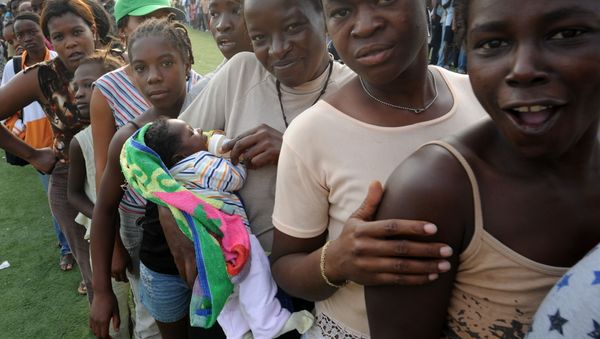 Women wait in line at a distribution point at the national stadium in Port-au-Prince on January 31, 2010. - Sputnik International