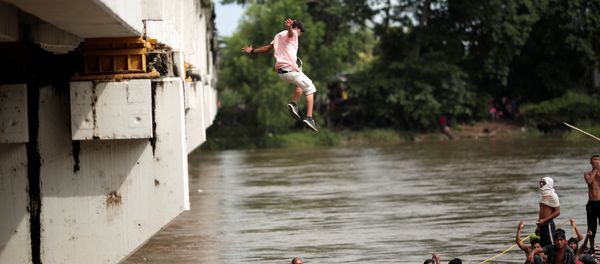 A Honduran migrant jumps from the bridge that connects Mexico and Guatemala to avoid the border checkpoint in Ciudad Hidalgo - Sputnik International