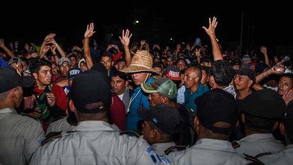 Honduran migrants taking part in a new caravan heading to the US, talk with Guatemalan police officers on their arrival to Chiquimula, Guatemala, on October 22, 2018 - Sputnik International
