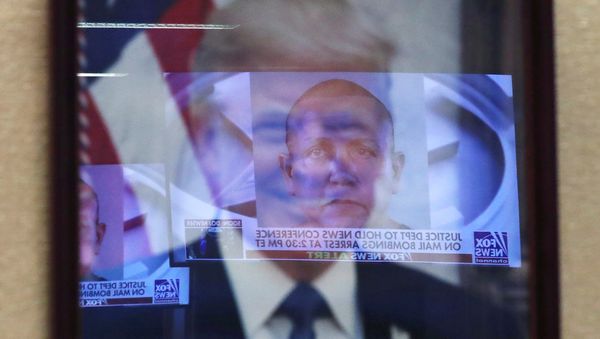 Televised pictures of parcel bombs suspect Cesar Sayoc are reflected in the official portrait of US President Donald Trump at the Justice Department in Washington DC, October 26, 2018 - Sputnik International