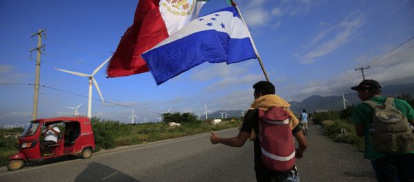 A migrant carrying the flags of Mexico and Honduras gives a thumbs-up to a moto rickshaw driver who stopped to take their picture, as a thousands-strong caravan of Central Americans hoping to reach the U.S. border moves onward from Juchitan, Oaxaca state, Mexico, Thursday, Nov. 1, 2018. Thousands of migrants resumed their slow trek through southern Mexico on Thursday, after attempts to obtain bus transport to Mexico City failed - Sputnik International