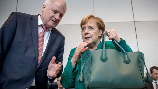 German Chancellor and leader of the Christian Democratic Union (CDU) Angela Merkel holds her hand bag as she confers with German Interior Minister Horst Seehofer at the beginning of a session on September 25, 2018 in the parliamentary compound of the Bundestag, where the parliamentary group is to elect their president German Chancellor and leader of the Christian Democratic Union (CDU) Angela Merkel holds her hand bag as she confers with German Interior Minister Horst Seehofer at the beginning of a session on September 25, 2018 in the parliamentary compound of the Bundestag, where the parliamentary group is to elect their president - Sputnik International