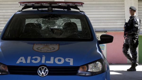 A policeman walks past a police car damaged during a protest at the Mangueira slum in Rio de Janeiro, Brazil August 11, 2015.  - Sputnik International