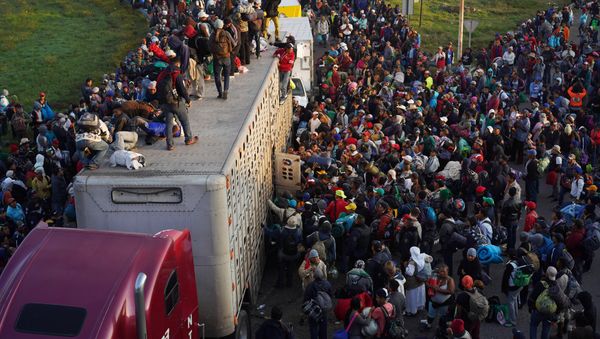 Migrants, part of a caravan of thousands traveling from Central America en route to the United States, try to catch a ride on a truck, in Irapuato, Mexico November 12, 2018 - Sputnik International