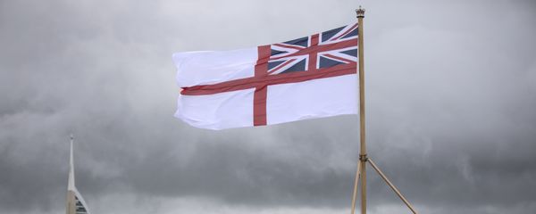 A naval officer looks up at the white ensign flying at the stern of the aircraft carrier HMS Queen Elizabeth, which has been beset with technical problems - Sputnik International
