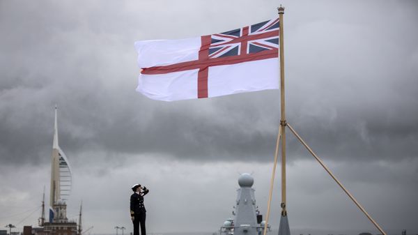 A naval officer looks up at the white ensign flying at the stern of the aircraft carrier HMS Queen Elizabeth, which has been beset with technical problems  - Sputnik International