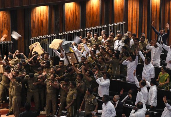 Sri Lankan police escort parliament speaker Karu Jayasuriya (C holding microphone) as aides hold up cushions to protect him and themselves from projectiles thrown by rival legislators in the assembly hall in Colombo on November 16, 2018 - Sputnik International