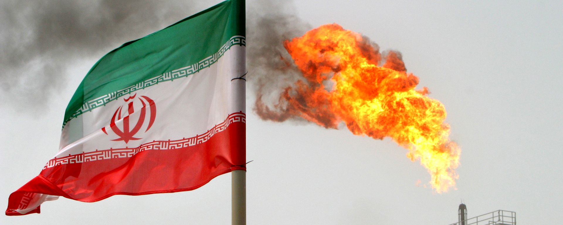 A gas flare on an oil production platform in the Soroush oil fields seen alongside an Iranian flag A gas flare on an oil production platform in the Soroush oil fields seen alongside an Iranian flag - Sputnik International, 1920, 25.10.2021