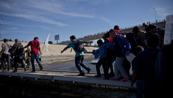 Migrants cross the river at the Mexico-U.S. border after getting past a line of Mexican police at the Chaparral crossing in Tijuana, Mexico, Sunday, Nov. 25, 2018 - Sputnik International
