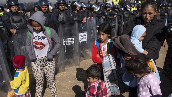 Migrants stand near Mexican police at the Mexico-U.S. border in Tijuana, Mexico, Sunday, Nov. 25, 2018, as they try to reach the US. - Sputnik International