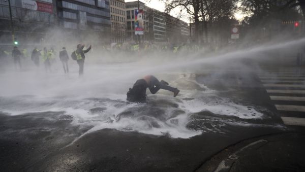 A demonstrator gets hit by a water cannon during a protest of the yellow jackets in Brussels, Friday, Nov. 30, 2018 - Sputnik International